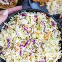 A bowl of coleslaw with shredded green cabbage, carrots, and red cabbage, ready to be served.