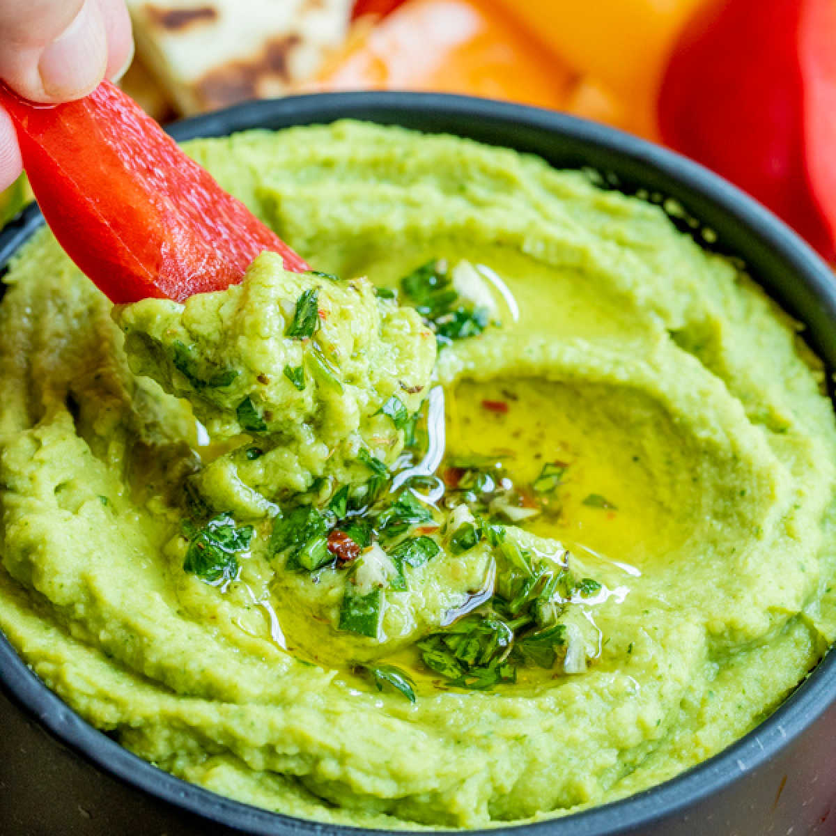 dipping into Avocado Hummus with a pepper