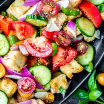 Panzanella Salad made with fresh garden vegetables and bread on a black platter