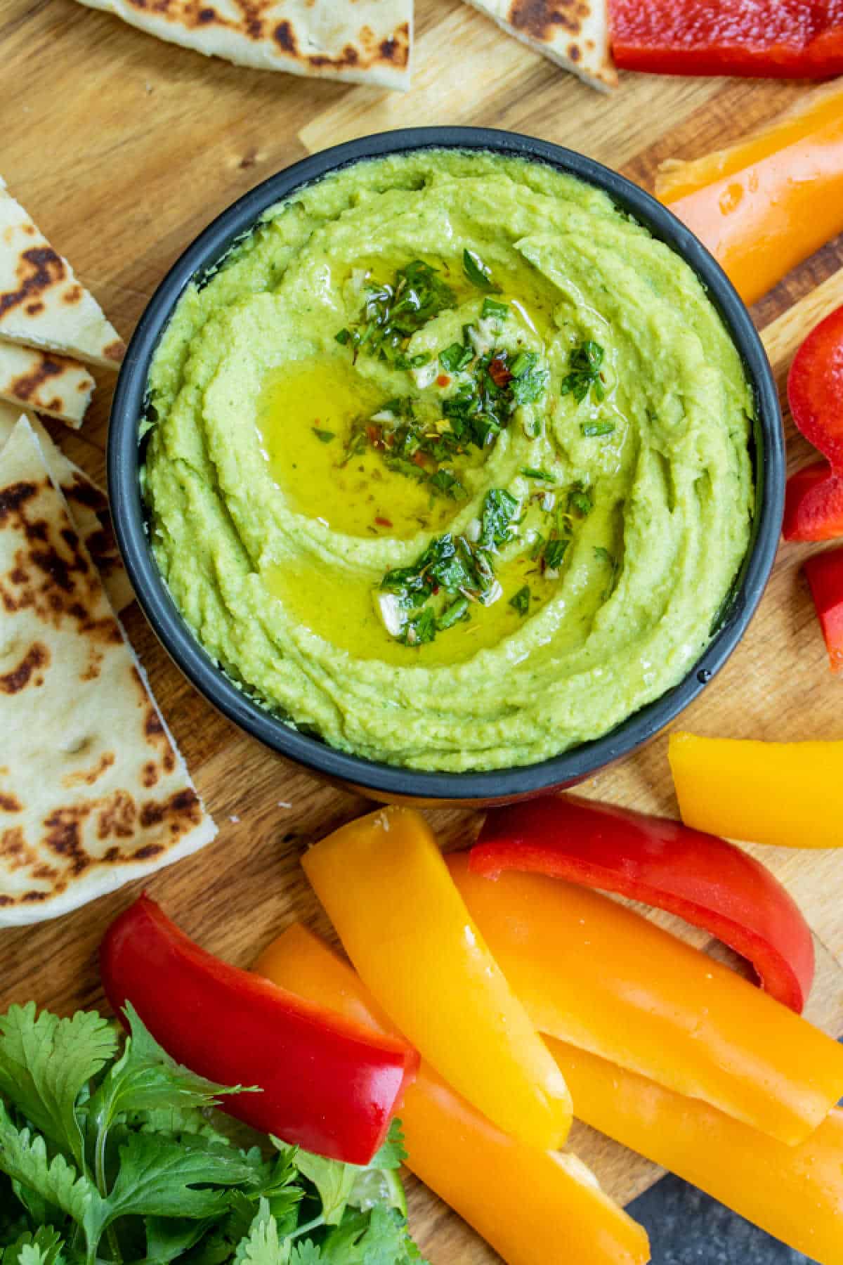 Avocado Hummus dip in a bowl with pita and peppers slices