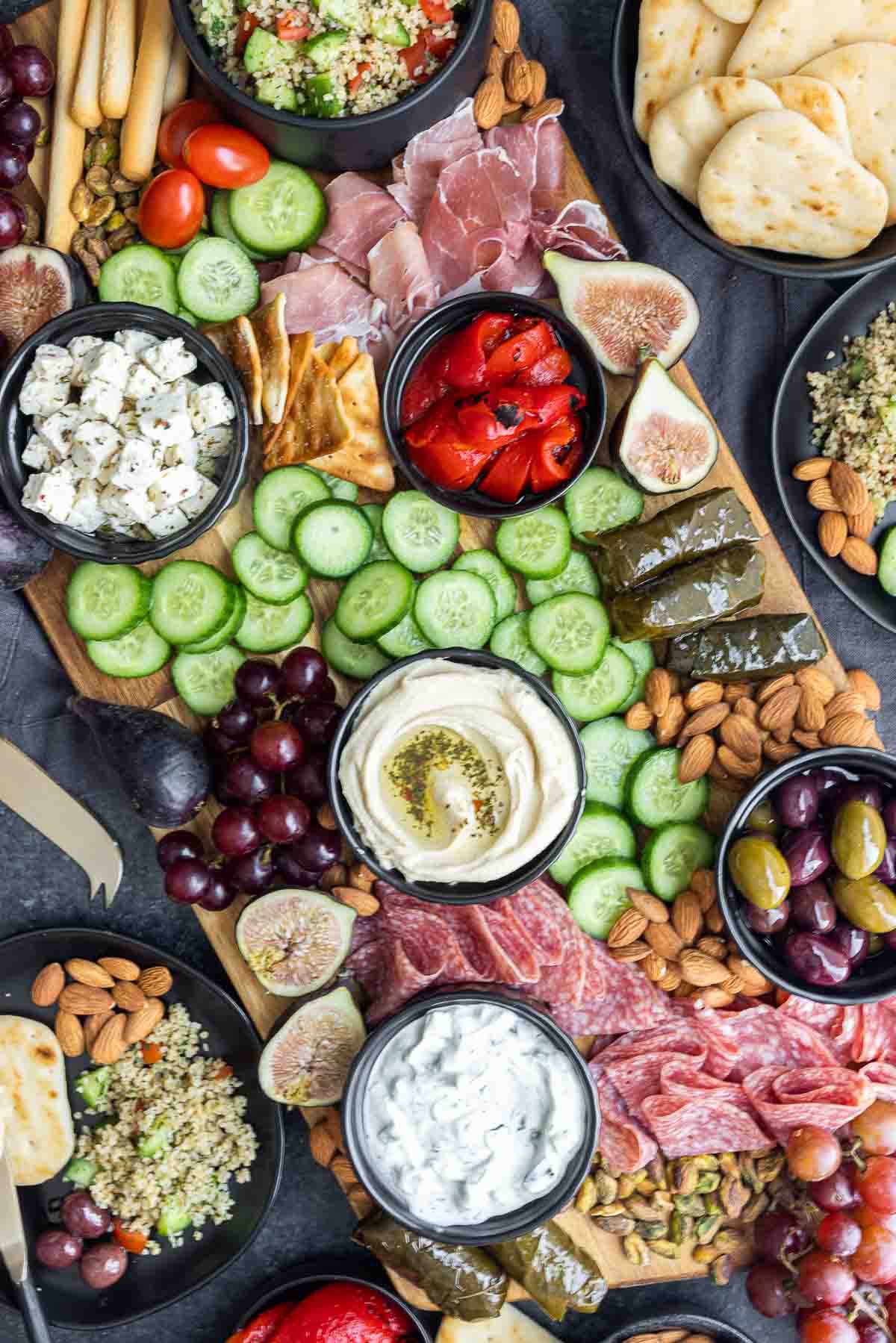 Mediterranean Mezze Platter on big wooden board covered in bite size fruits and vegetables