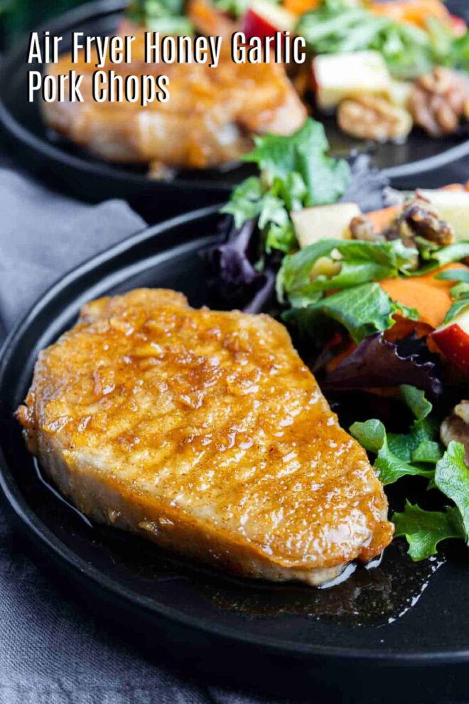 pinterest image of Air Fryer Honey Garlic Pork Chops on a plate with salad