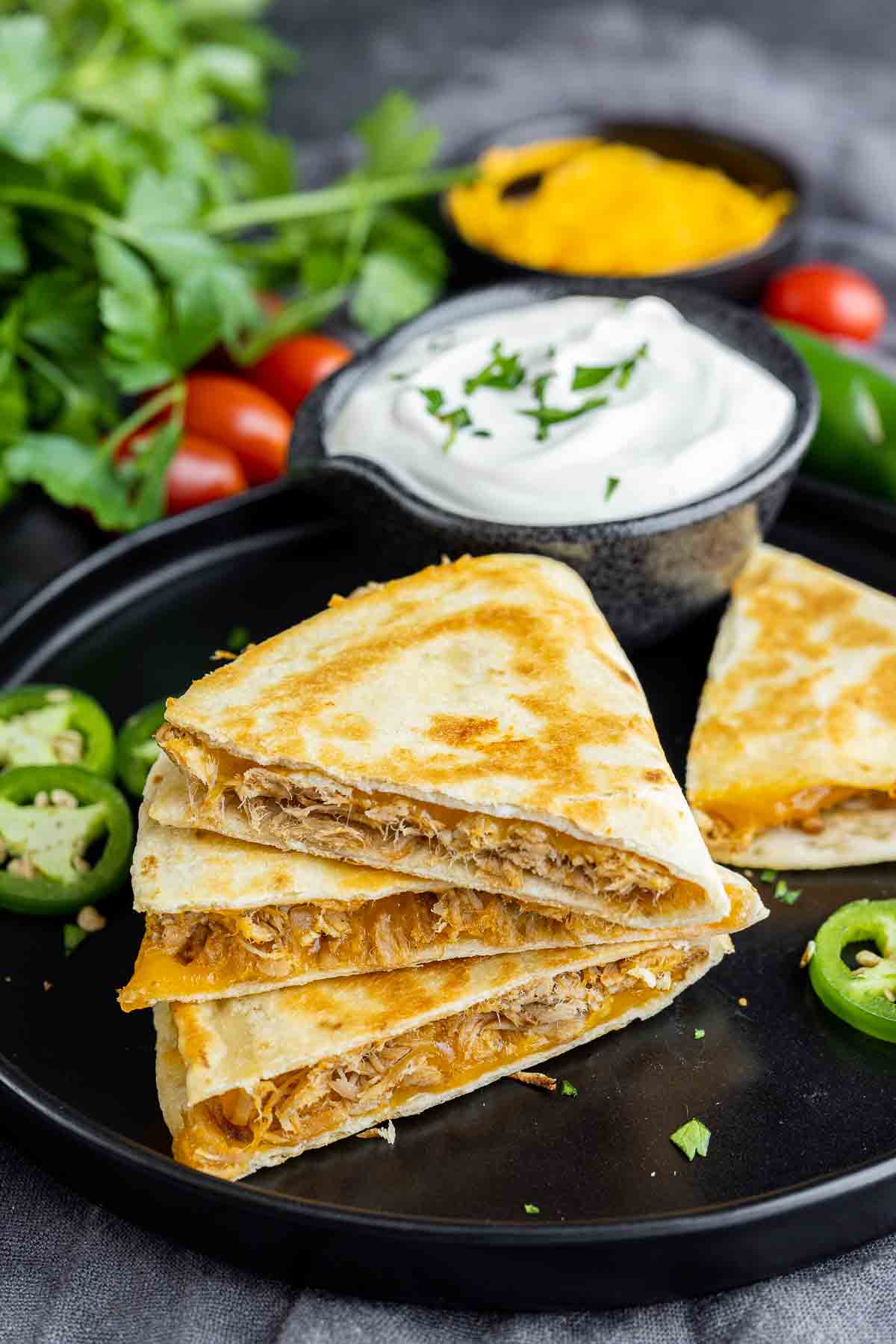 Pulled Pork Quesadillas on a black plate with sour cream