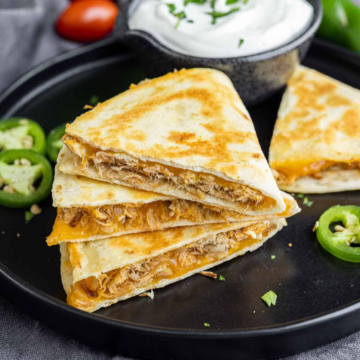 Pulled Pork Quesadillas on a black plate with jalapeno slices