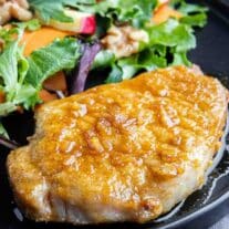 Air Fryer Honey Garlic Pork Chops on a black plate with walnut salad