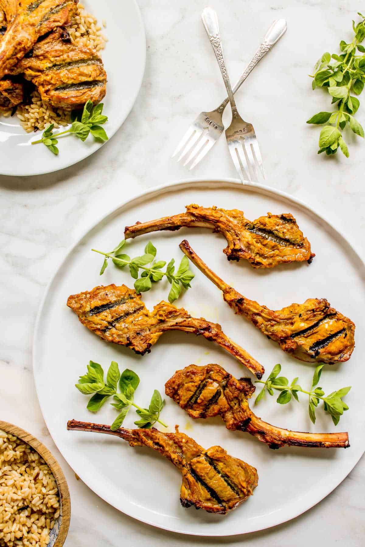 Grilled Lamb Chops in a Curry Marinade on a round platter with herbs