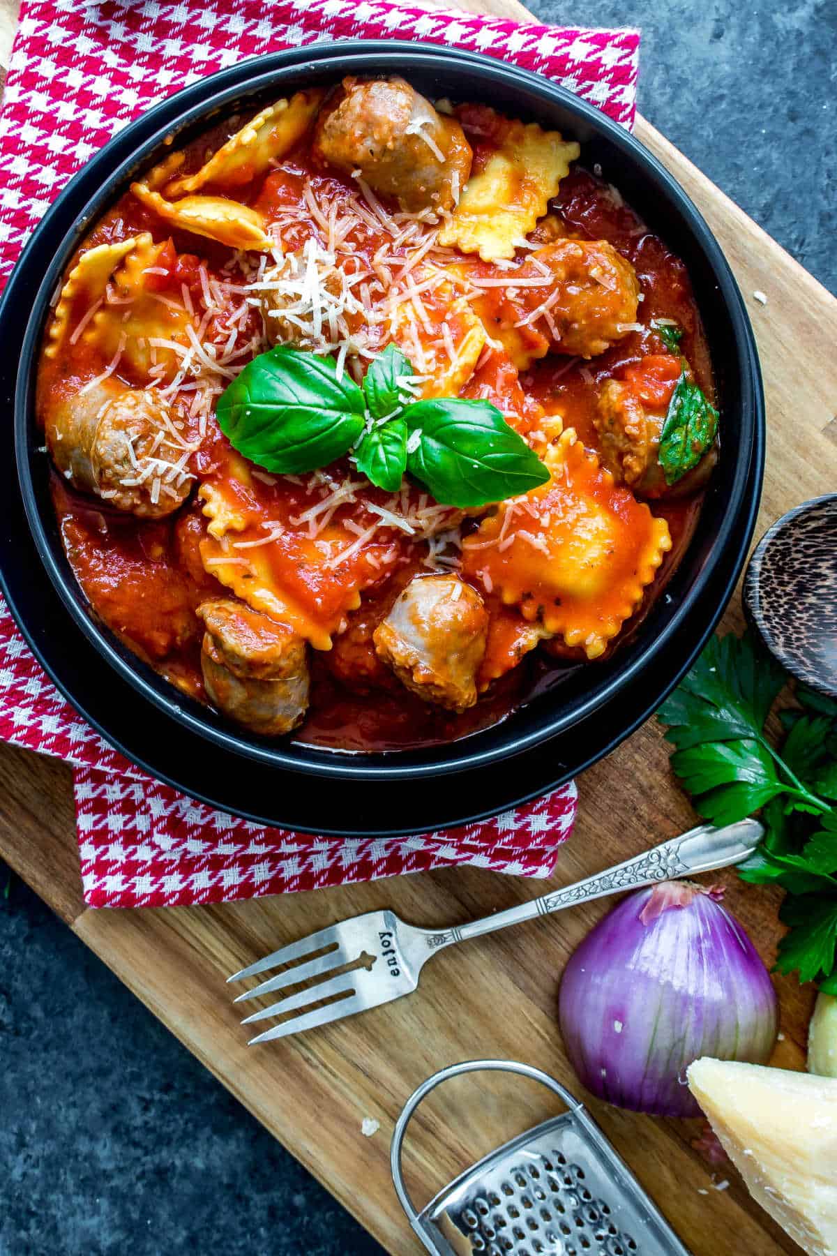 bowl of Ravioli and Sausage Slow Cooker Casserole on wood board