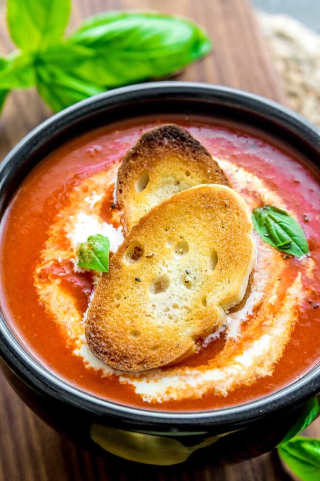Roasted Red Pepper Soup in a black bowl with crostini