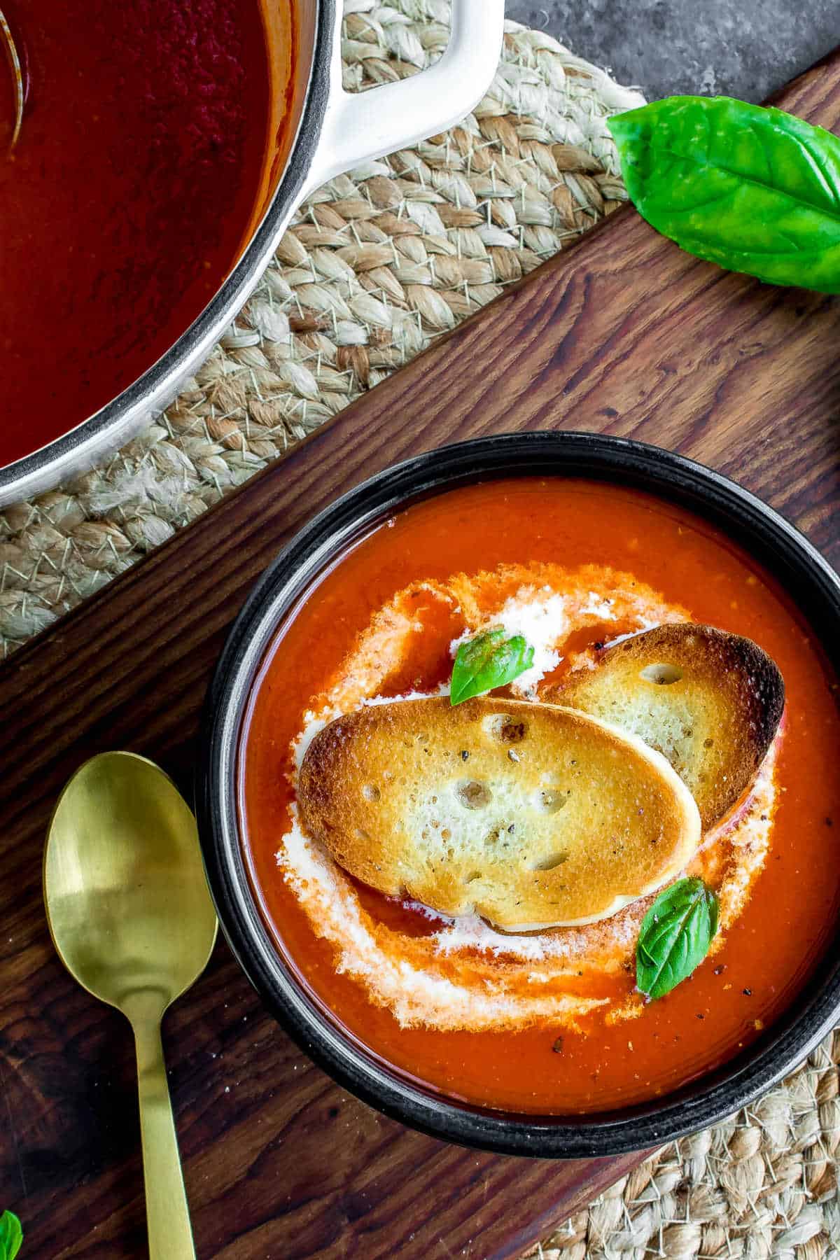 Roasted Red Pepper Soup in a black bowl with gold spoon