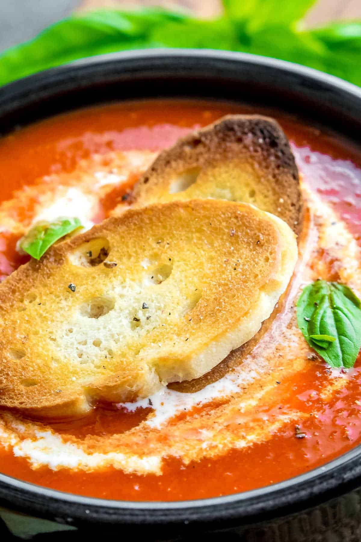 Roasted Red Pepper Soup in a black bowl with crostini