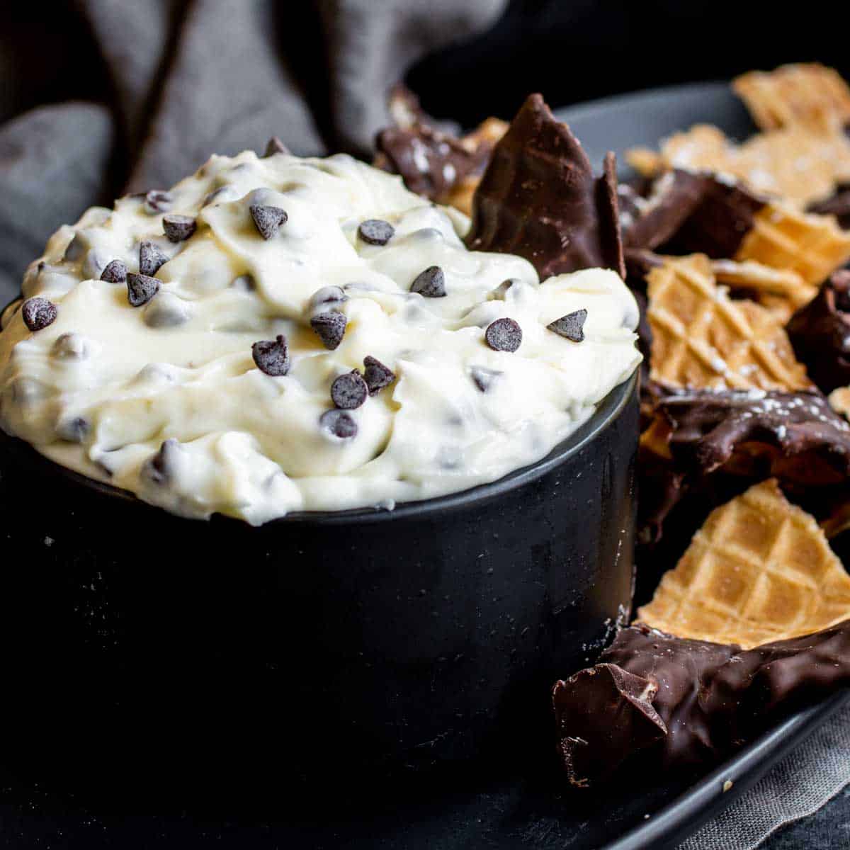 waffle cone chip in Cannoli Dip in black bowl