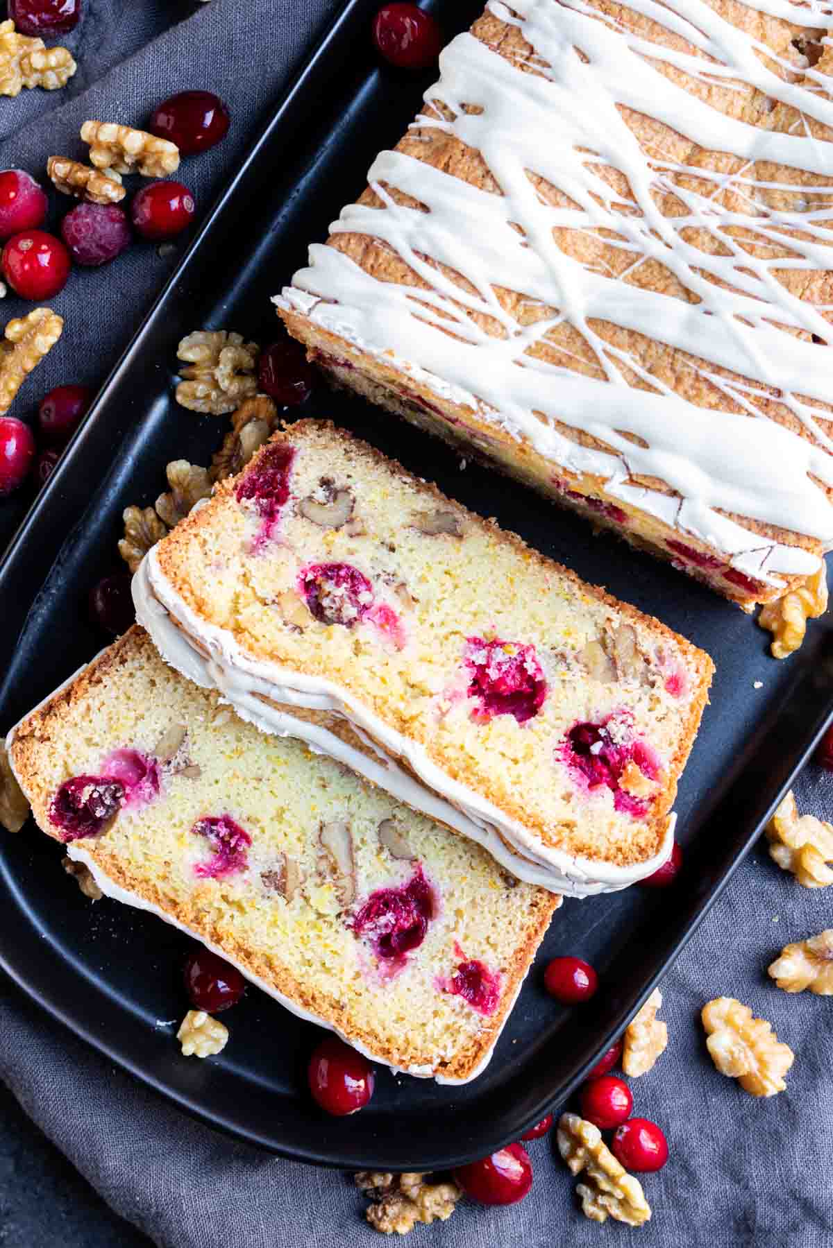 Cranberry Orange Bread on black platter with nuts and cranberries