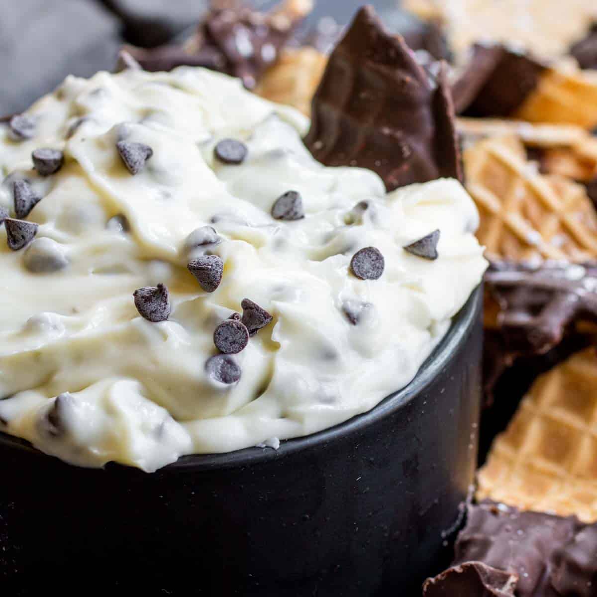Cannoli Dip in a black bowl with chocolate chips
