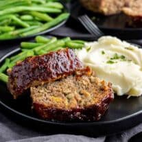 a black plate with Air Fryer Meatloaf, mashed potatoes and green beans