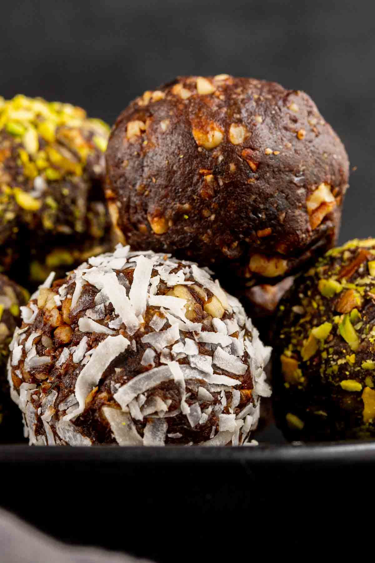 date balls rolled in coconut on black plate