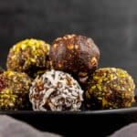 date balls rolled in coconut on black plate
