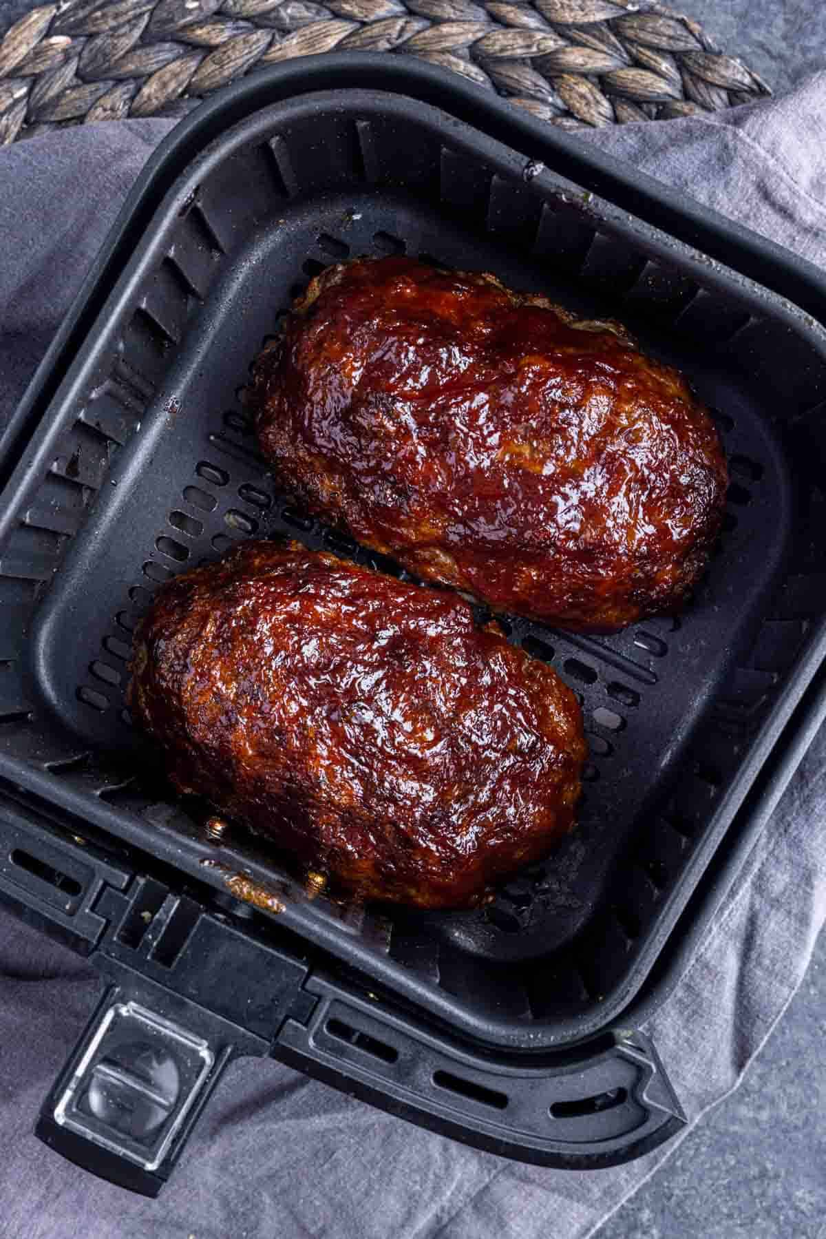 2 small cooked Air Fryer Meatloaf in air fryer basket