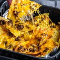 pulling Air Fryer Nachos out of the air fryer basket