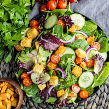 top down view of mixed green salad in black bowl