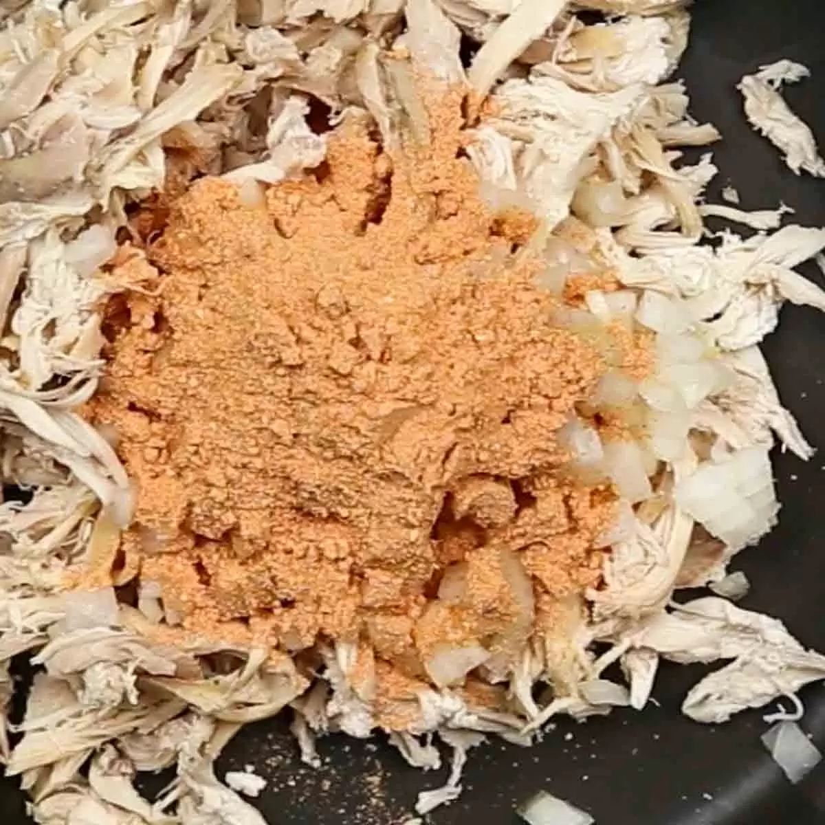 cooking chicken, onions and taco seasoning for Chicken Enchilada Casserole