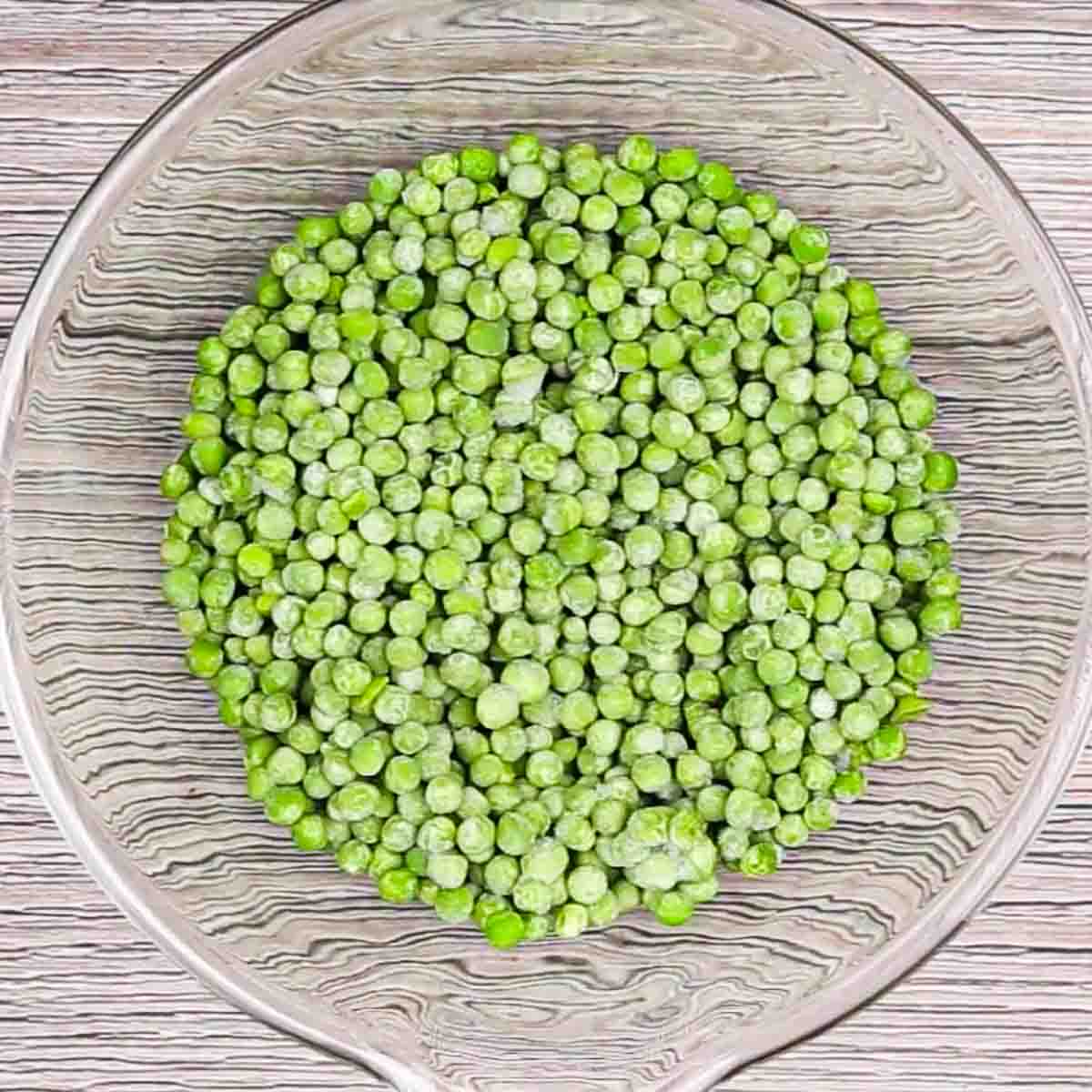 a glass bowl of frozen peas to make english pea salad