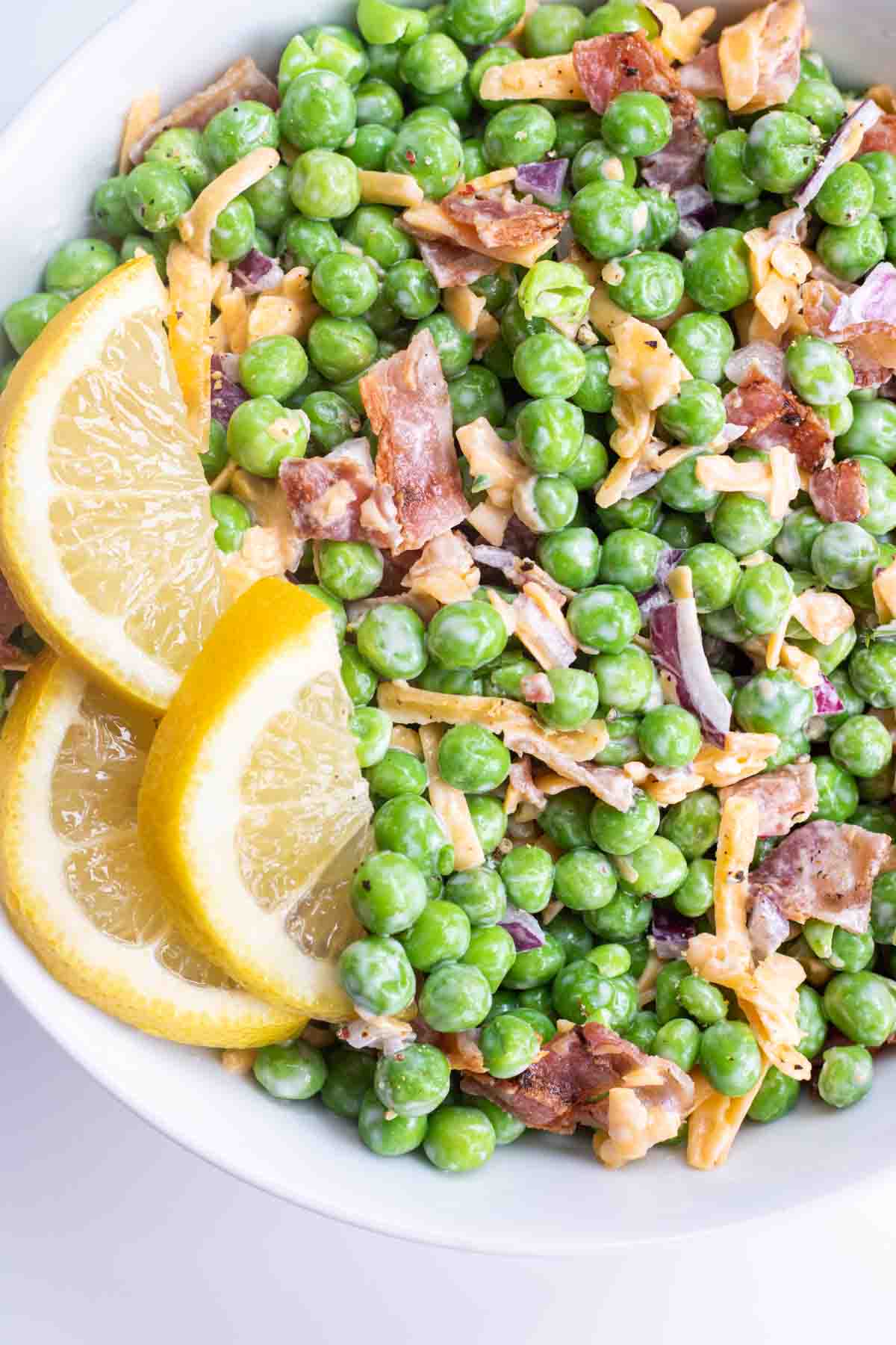 english pea salad in a white bowl with lemon slices