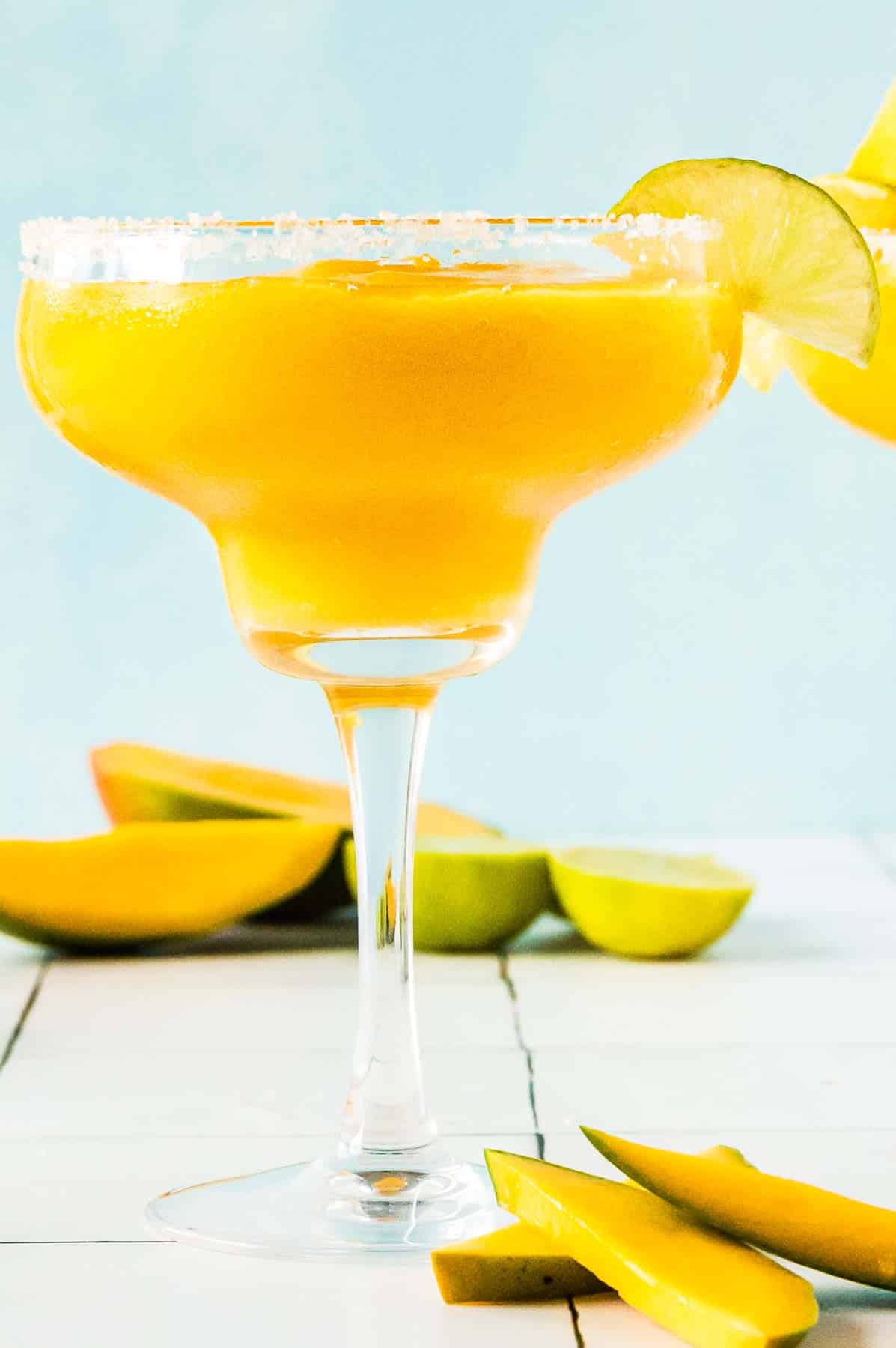 Frozen Mango Margarita in a glass with a salted rim and lime wedge