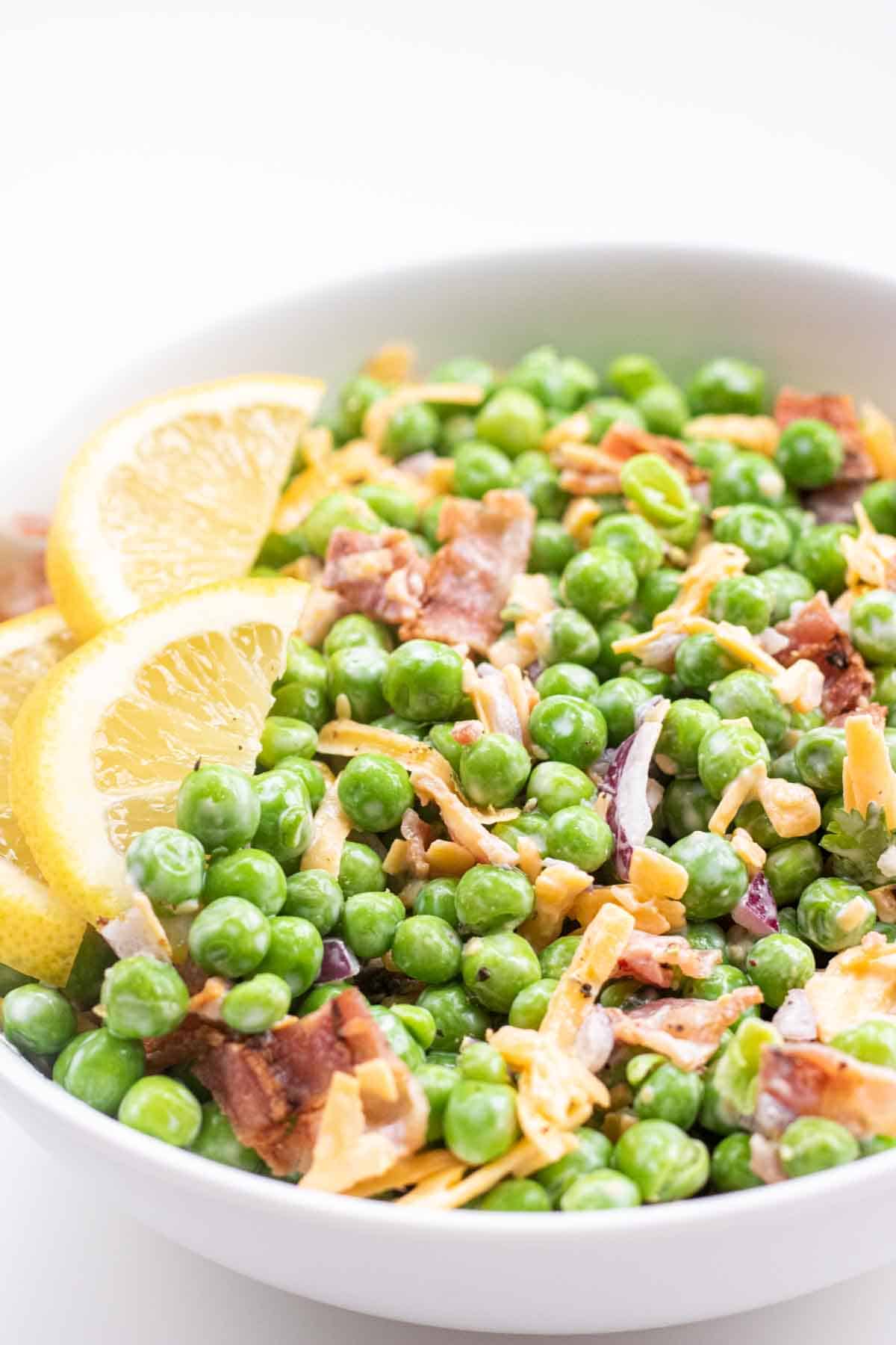 english pea salad in a white bowl with bacon and cheddarcheese