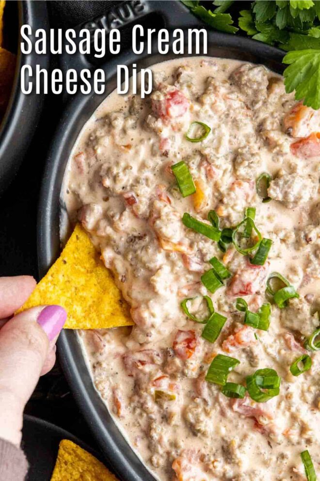 pinterest image of dipping into Sausage Cream Cheese Dip with a corn tortilla chip
