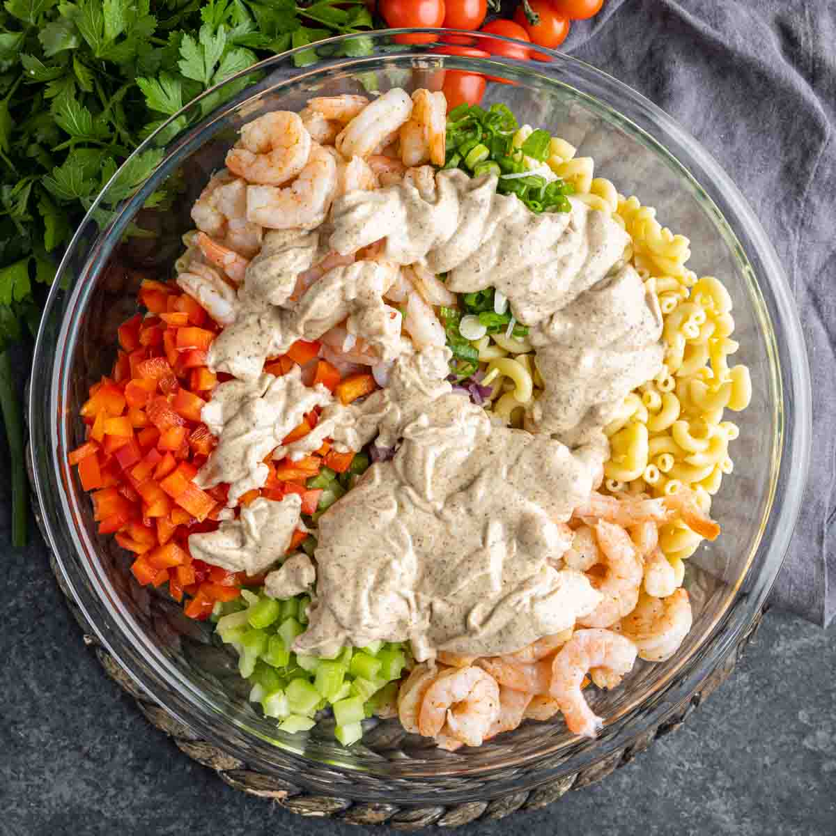 Shrimp Pasta Salad ingredients in a glass bowl with dressing