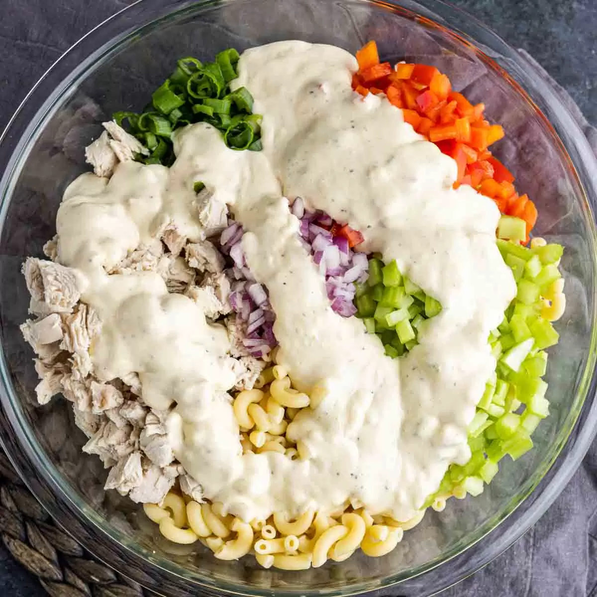Chicken Macaroni Salad ingredients in a bowl with dressing poured on top