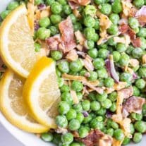 english pea salad in a white bowl with lemon slices