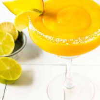 Frozen Mango Margarita in a glass garnsihed with a lime and mango wedge