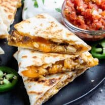 Chicken Quesadilla on a black plate with salsa