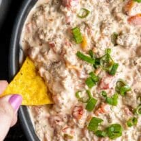 dipping into a bowl of Sausage Cream Cheese Dip