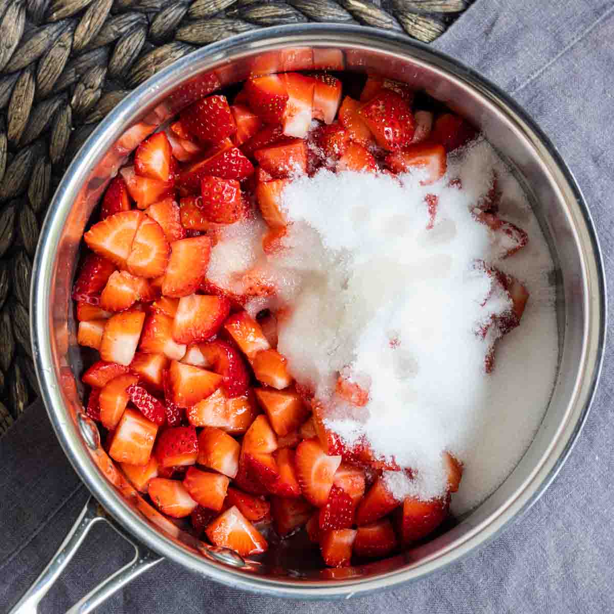 pot with chopped up strawberries and sugar to make Strawberry Coulis