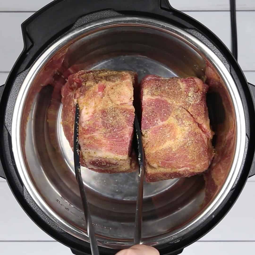 adding the pork shoulder in the pressure cooker to make Instant Pot Pulled Pork