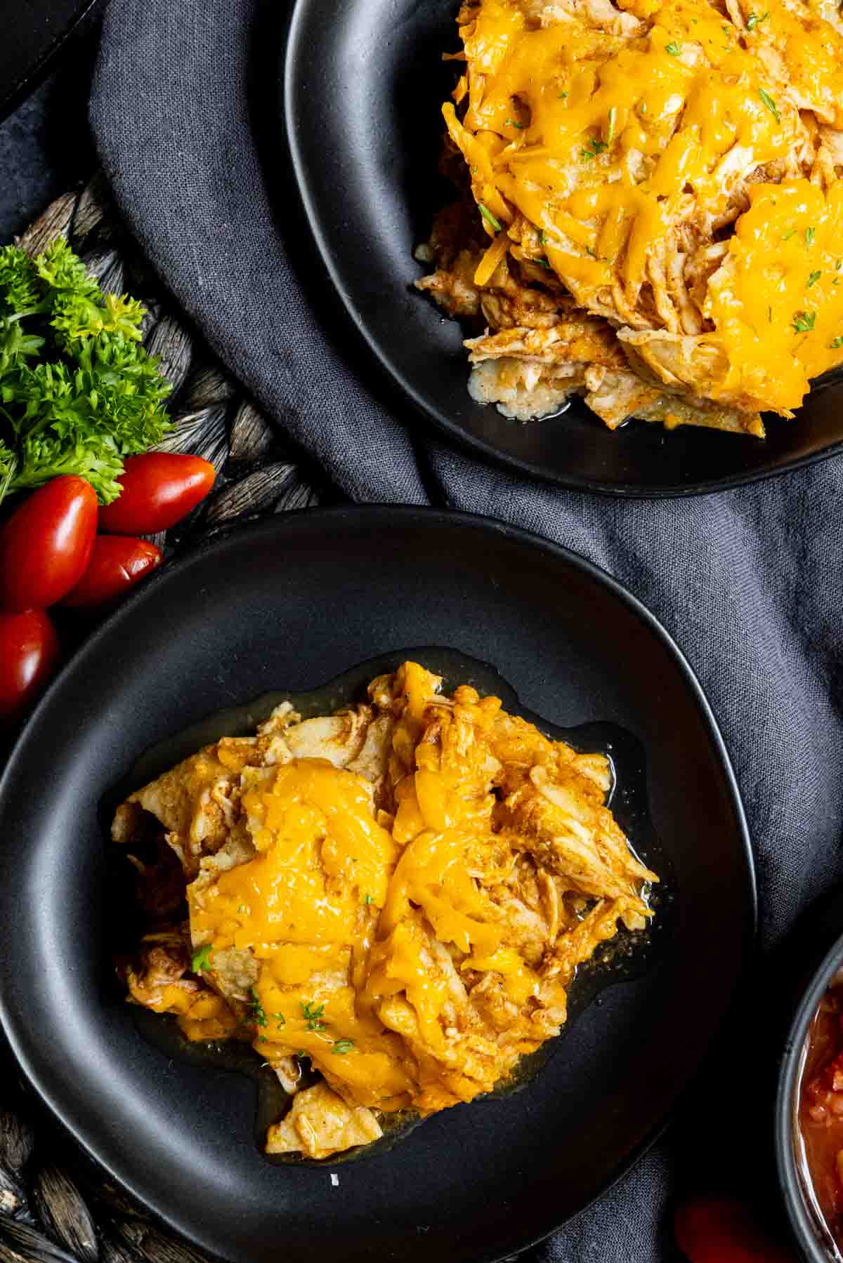 black plates with Crock Pot Chicken Enchiladas with parsley and tomatoes