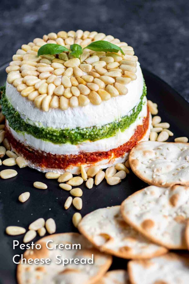 pinterest image of Pesto Cream Cheese Spread on a black platter with crackers