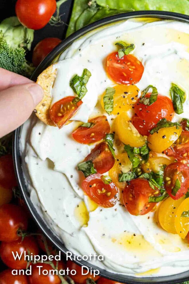 pinterest image of dipping a cracker in Whipped Ricotta and Tomato Dip