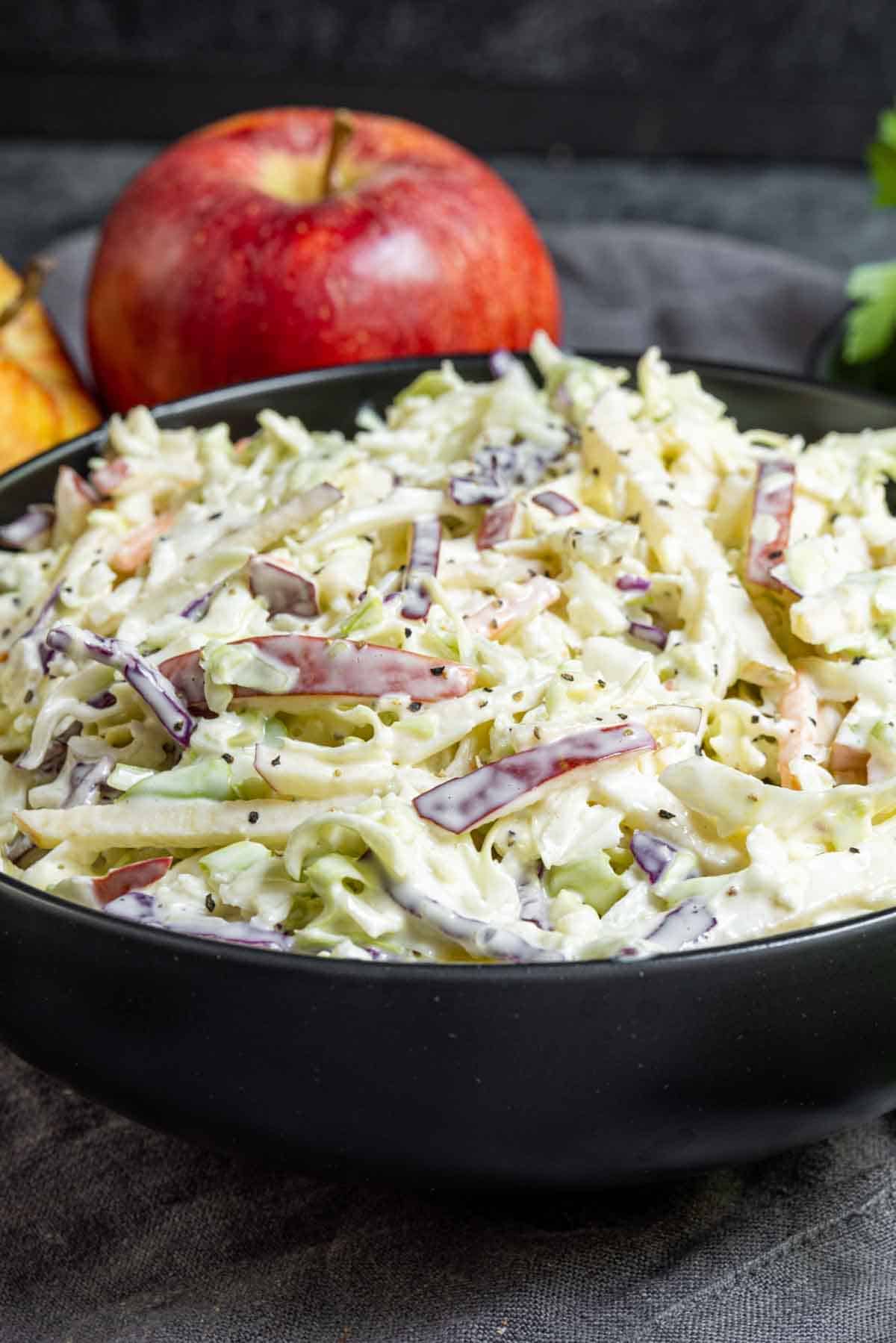 bowl of Apple coleslaw with one apple in background