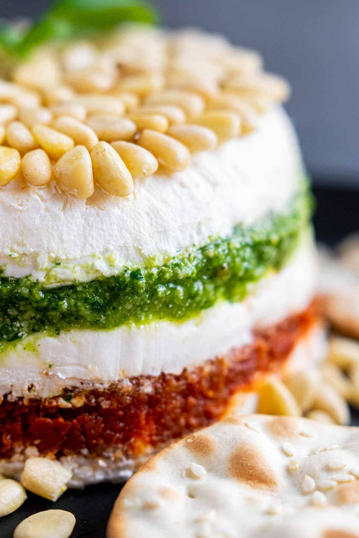 Pesto Cream Cheese Spread layers garnished with pine nuts on top