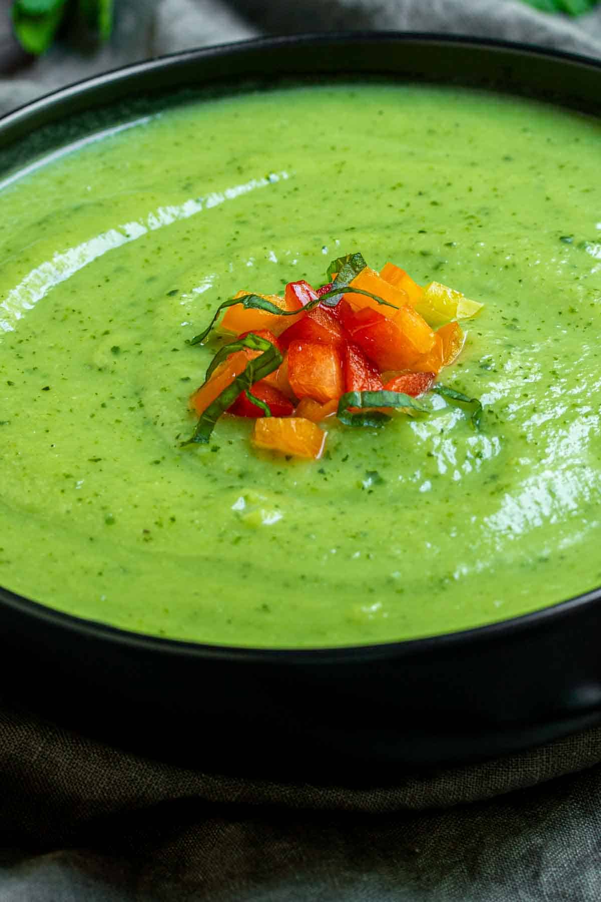 chopped bell peppers on top of a bowl of Zucchini Soup