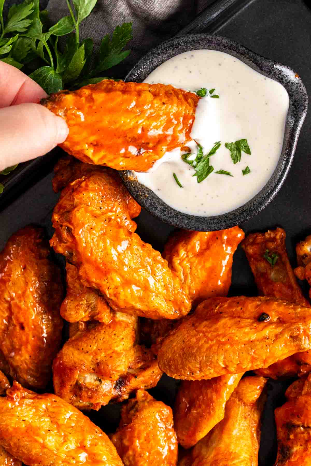 A person dipping Air Fryer Chicken Wings in a creamy sauce.