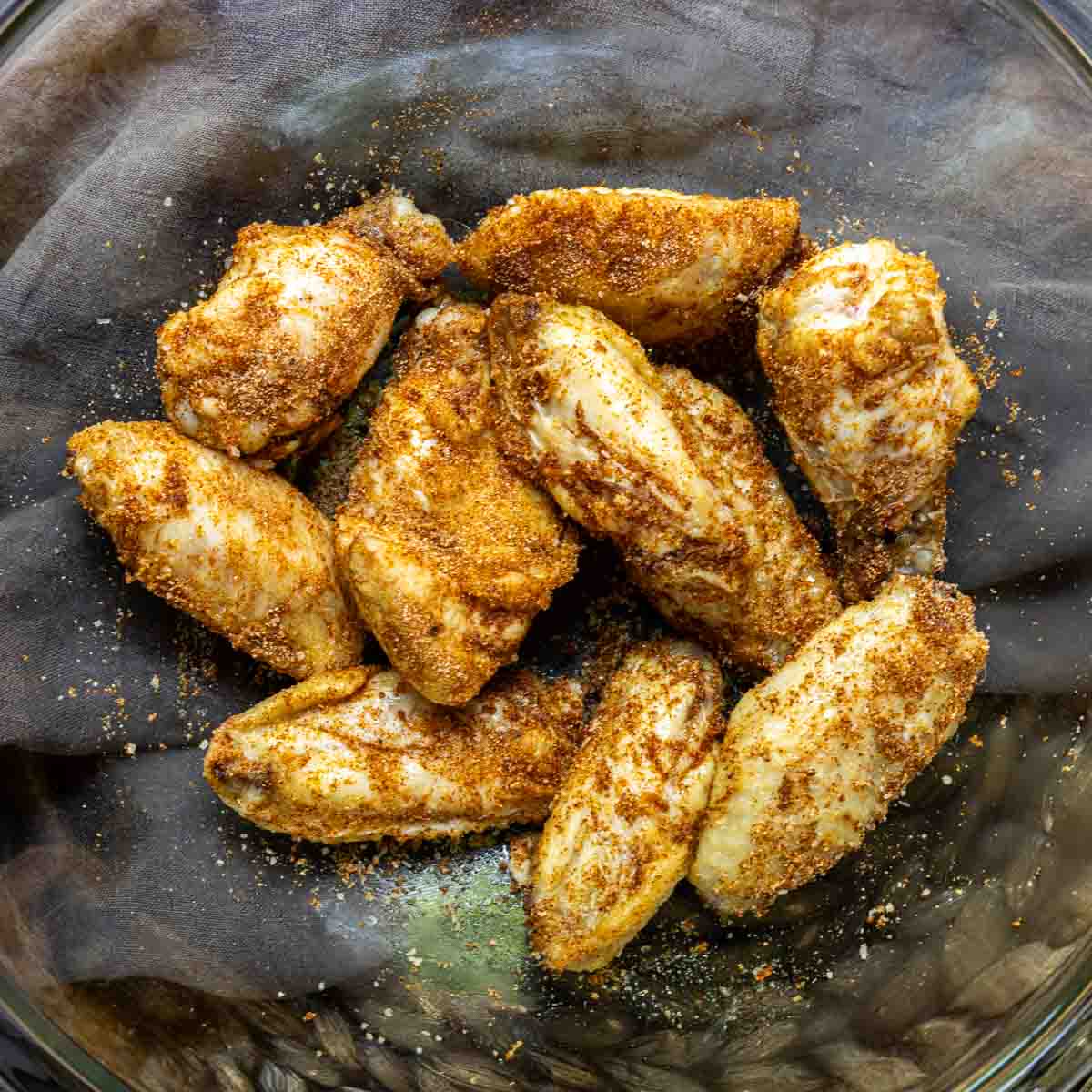 Frozen Chicken Wings in the Air Fryer in a glass bowl with seasoning.