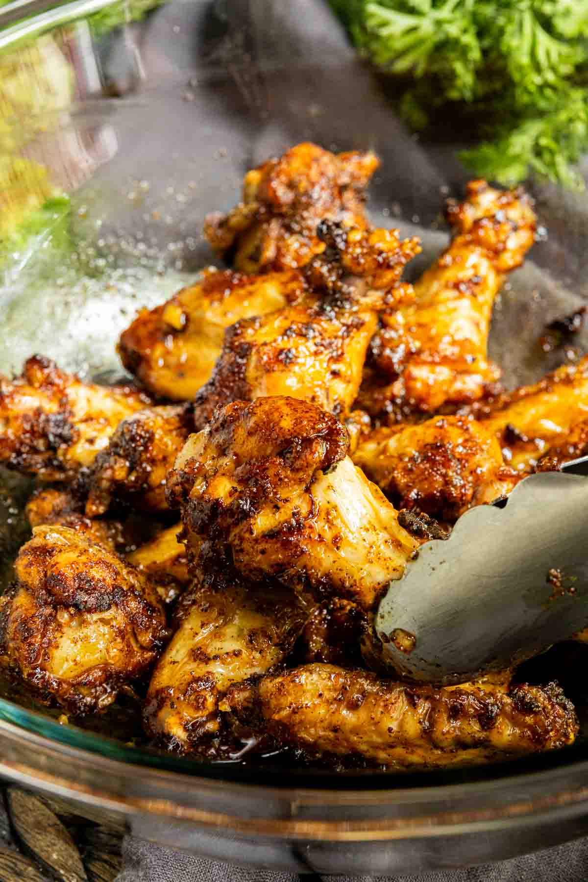 Honey Garlic Chicken Wings in a glass bowl with tongs