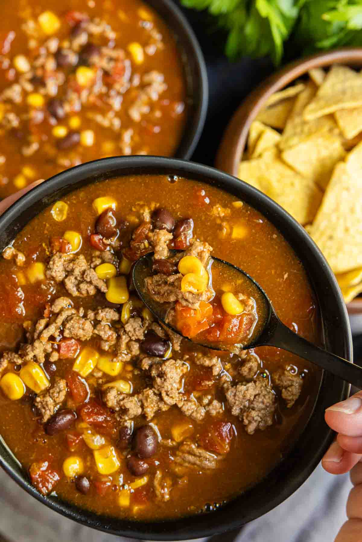 A bowl of Instant Pot Taco Soup with corn tortillas and tortilla chips.
