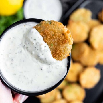 A hand holding a bowl of aioli dipping sauce.