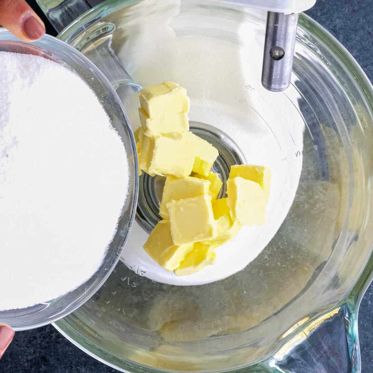 A person mixing butter and sugar in a bowl.