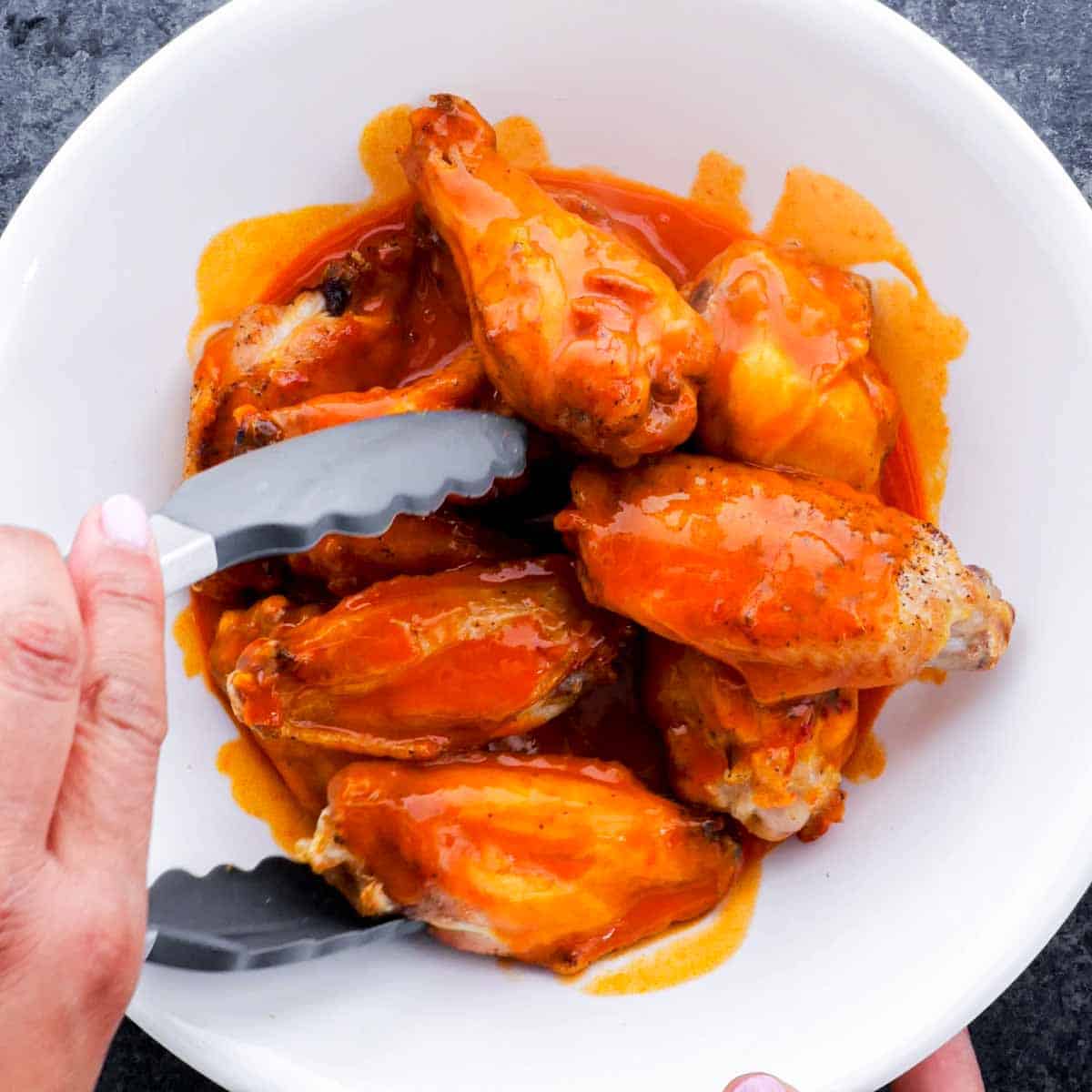 Air Fryer Chicken Wings in a white bowl with a tongs